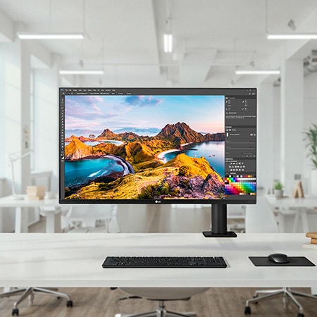 LG Monitor 32UN880K in a dark finish positioned at the center of a bright open-office setup on a white desk, displaying photo editing software for efficient professional work.