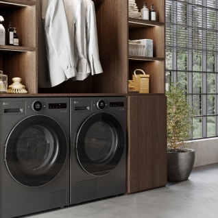 In the laundry room, a black LG washing machine and dryer are placed side by side, next to a wood-tone drawer topped with various detergents and shirts.	