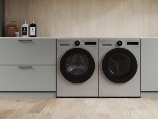 In the laundry room, a white LG washing machine and dryer are stacked on top of each other, with various books and plants arranged to the left.	