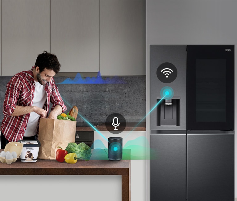 Man unpacking groceries in a kitchen with an LG smart refrigerator and voice-activated smart speaker on the counter.