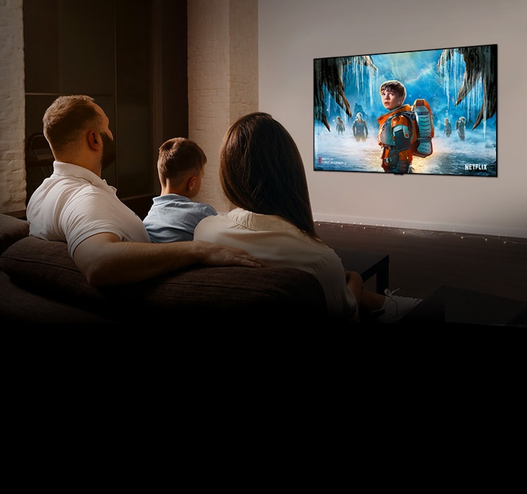 Couple sitting on a sofa in the living room watching a romantic movie on TV