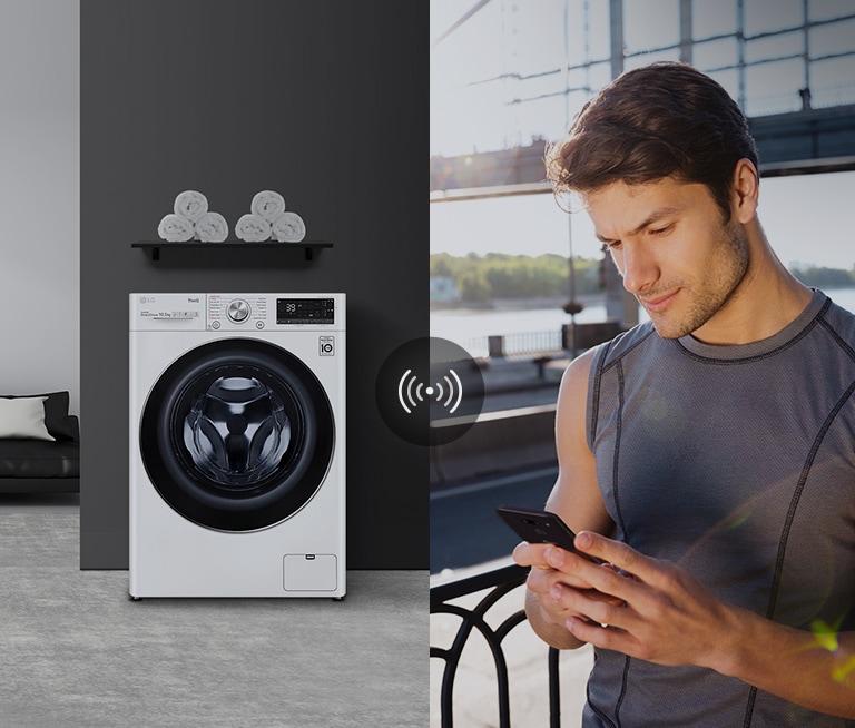 A woman sitting on the couch and drinking tea is giving orders to her washing machine through her AI speaker.