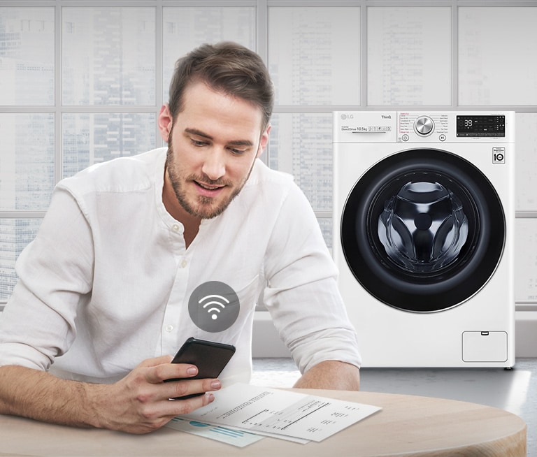 A man is monitoring the condition of the washing machine through a mobile phone app.