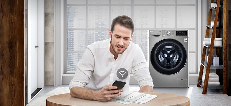 A man is monitoring the condition of the washing machine through a mobile phone app.