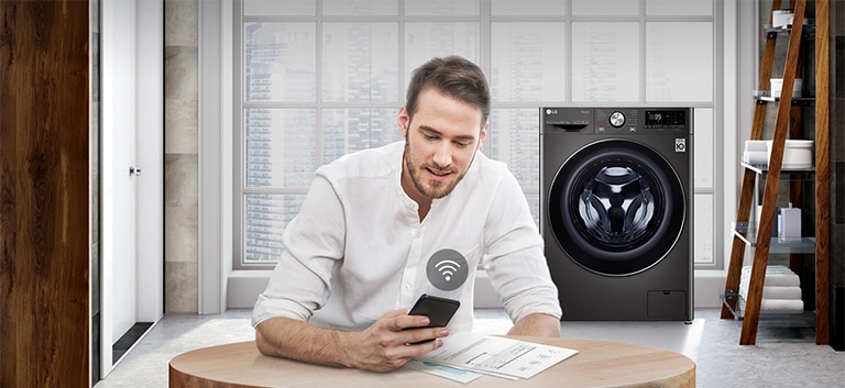 A man is monitoring the condition of the washing machine through a mobile phone app.