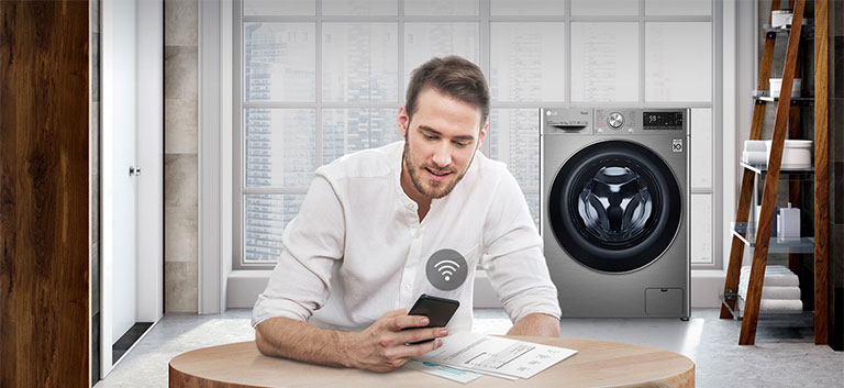 A man is monitoring the condition of the washing machine through a mobile phone app.