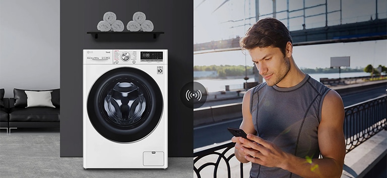 A man outdoors is checking the condition of a washing machine at home through a mobile phone app.