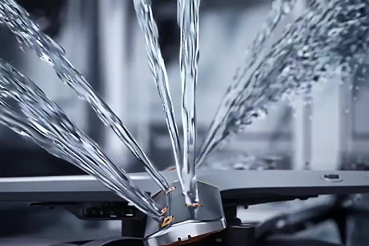 Footage of intense water streams from rotating dishwasher blades in close-up.