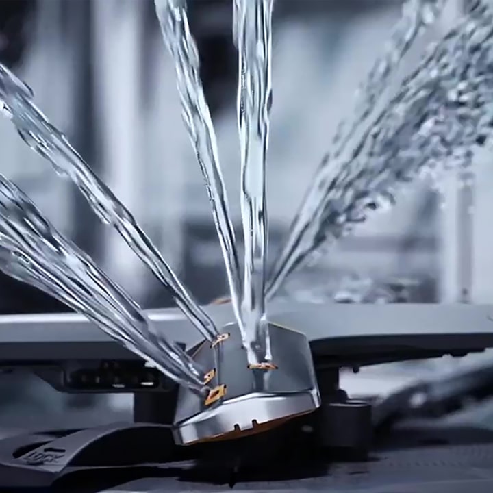 Footage of intense water streams from rotating dishwasher blades in close-up.