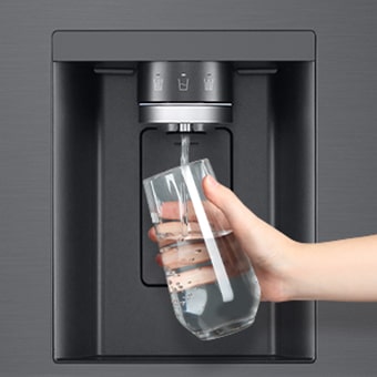 A person is getting water from the refrigerator dispenser in a cup