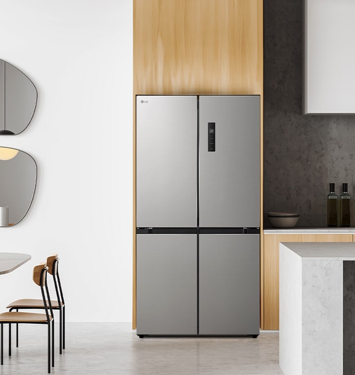 Modern kitchen with lg multi-door refrigerator in a sleek, silver finish, accompanied by a round dining table with wooden chairs, including abstract mirrors and minimalist furnishings.