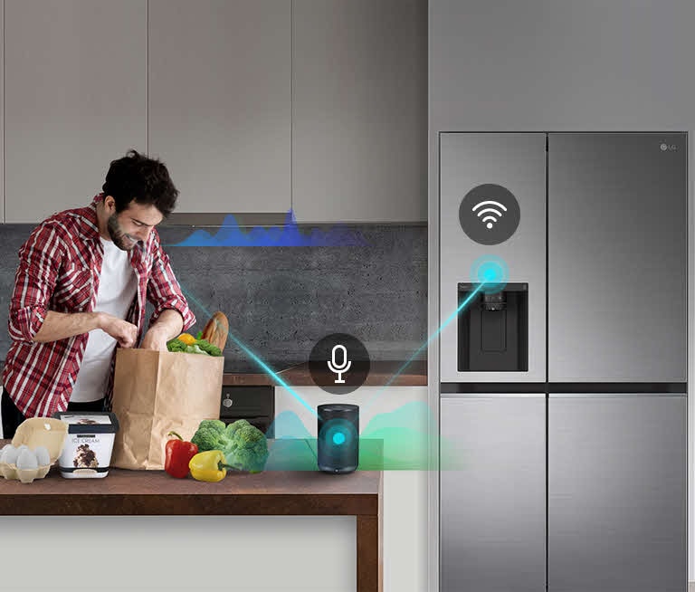 A man stands in a kitchen unloading produce from a grocery bag and speaks, shown by volume bars moving up and down near him, to the AI speaker on the counter telling it to "turn on express freeze". A line appears that goes from the man to the AI speaker which has a microphone icon above it. Then volume bars show up near the AI speaker and a line appears from the AI speaker to the refrigerator which has a Wifi icon above it.