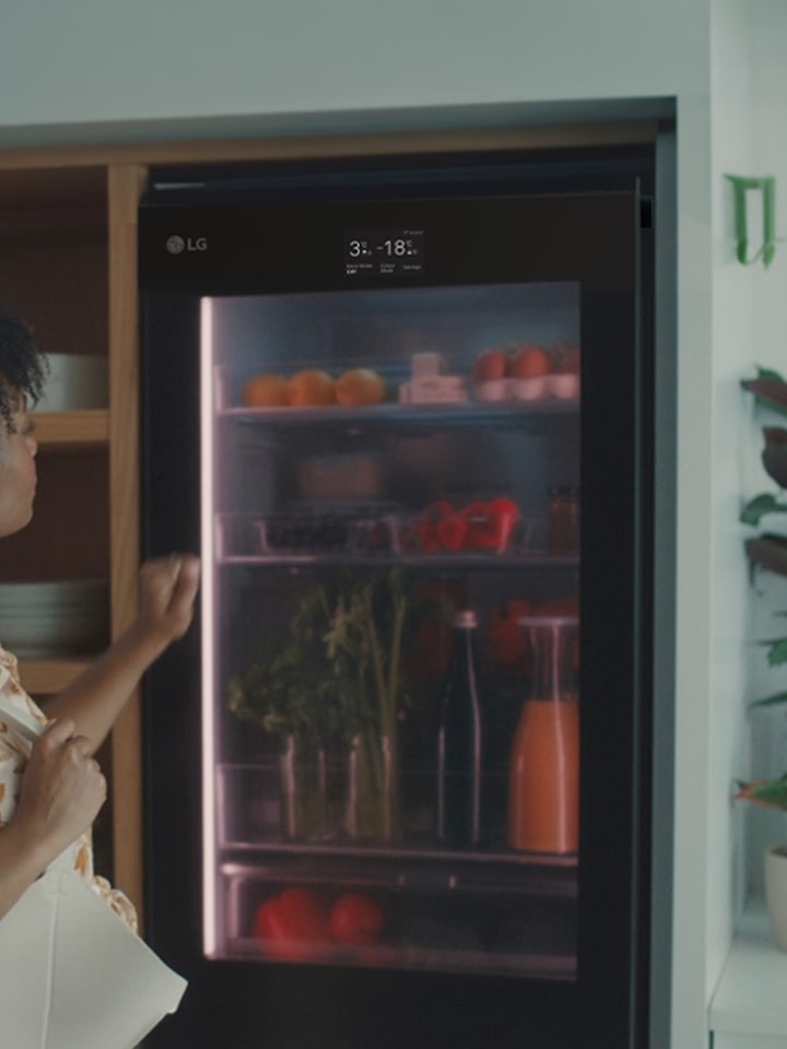 Image of a woman knocking on the top of a refrigerator.	