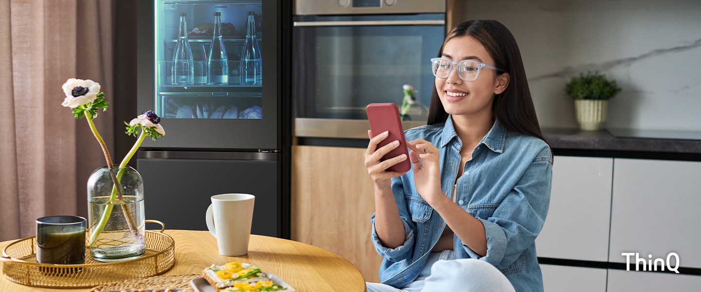 An image of a woman touching her phone in the kitchen.