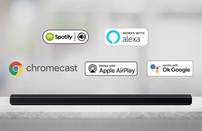 There is a soundbar placed on a gray shelf and there are AI platform logos, in order of Spotify, Alexa, Chromecast, Apple Airplay, and OK Google from left to right.