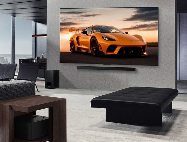 Spacious living room with a view of a cityscape. LG OLED TV is mounted on the wall with an LG Soundbar. The TV's Ultra Slim Design is showcased. Zero Connect Box is visible, but concealed.
