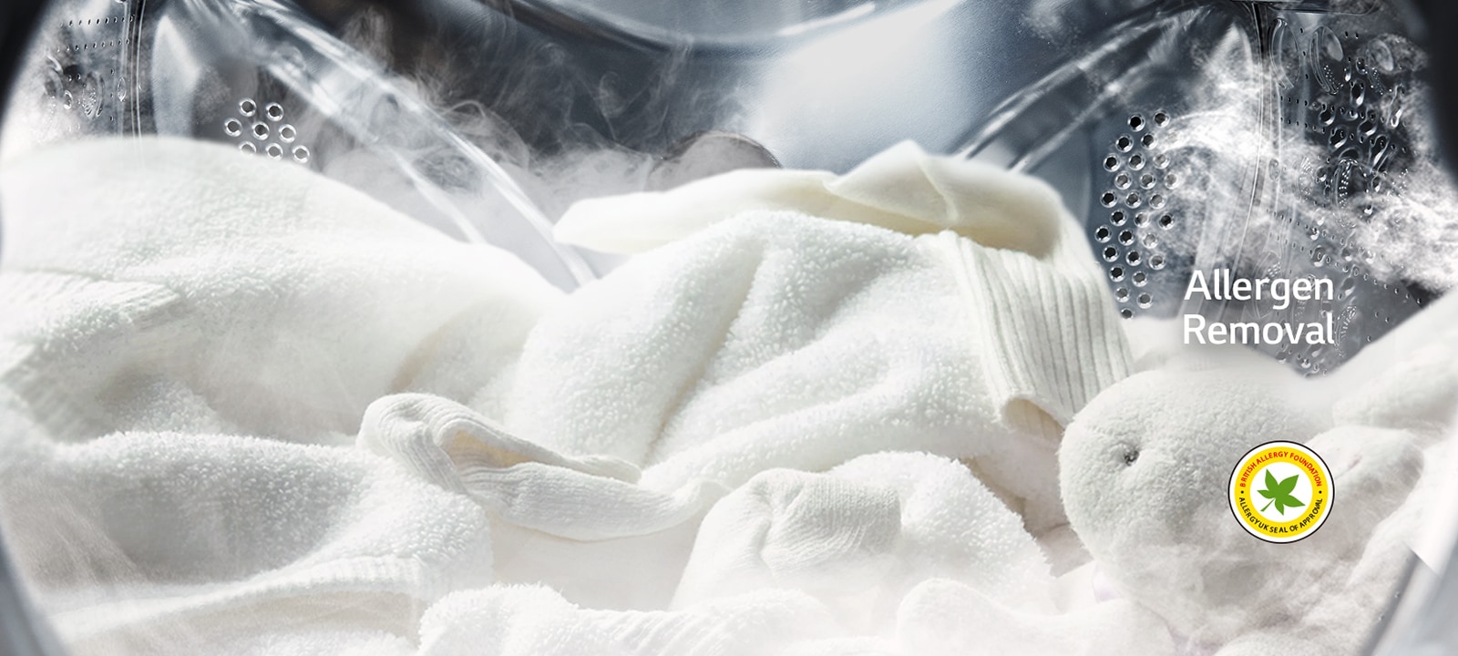 A soft white robe and stuffed animal are shown with steam in the drum of the washing machine.