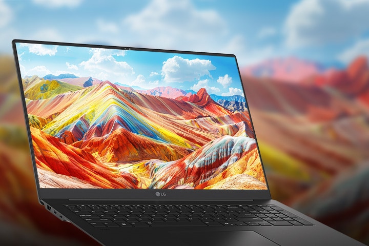 A laptop displaying a vivid and colourful landscape of vibrant mountains on its screen, emphasising high-resolution and rich colour reproduction. The background features a blurred version of the same landscape, drawing attention to the screen quality.