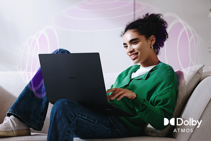 A person sitting on a couch, enjoying immersive audio while using an LG gram laptop. The text highlights Dolby Atmos technology, emphasising a rich, expansive, 360-degree auditory experience. Surrounding sound waves in the background visually represent the immersive soundscape.