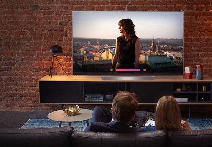 An image shows a couple watching lg super uhd tv and testing the voice command from its artificial intelligent feature. 