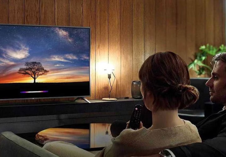 A couple watches the LG TV in their home cinema room.