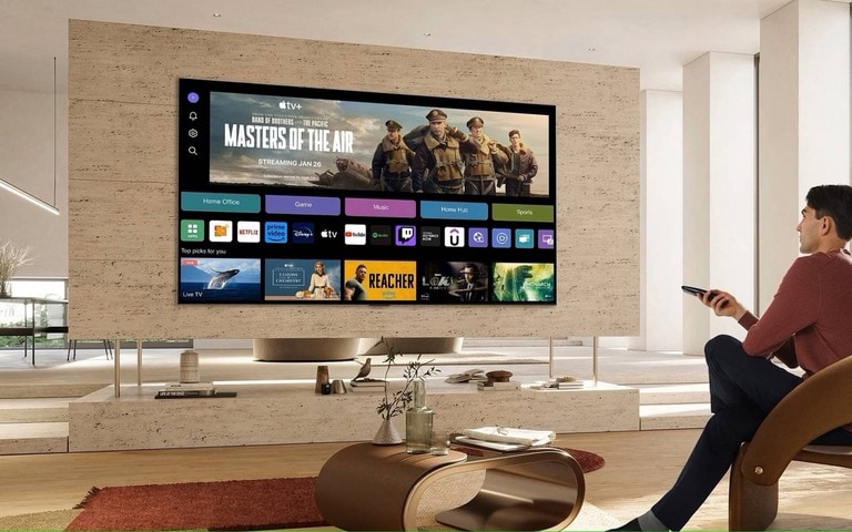 Man enjoying a smart TV experience with an LG AI TV featuring a user-friendly interface and streaming options in a contemporary living room.