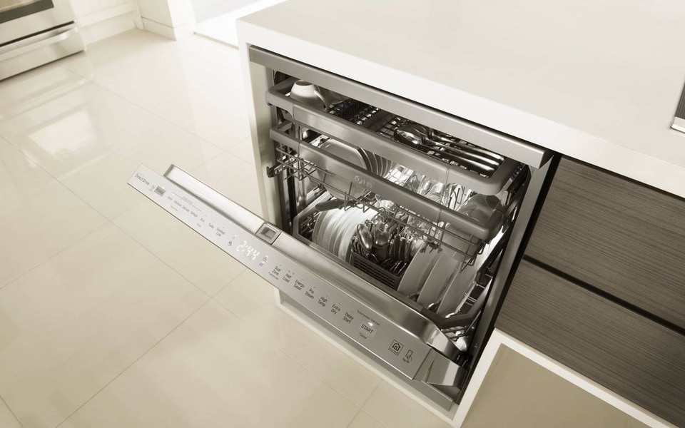 An open LG dishwasher integrated into a modern kitchen, showcasing neatly organized dishes and utensils with a sleek stainless steel finish and intuitive control panel