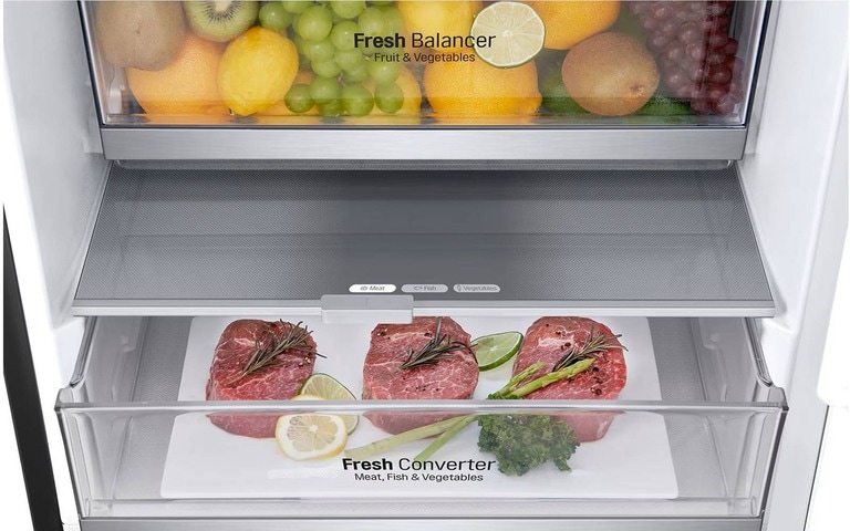 Interior of an LG fridge with two clear drawers. The top drawer is filled with colourful fruits like lemons, grapes, and kiwis, labelled "Fresh Balancer." The bottom drawer contains neatly arranged raw steaks garnished with herbs, labelled "Fresh Converter." The sleek design emphasises organised, fresh storage for various foods.