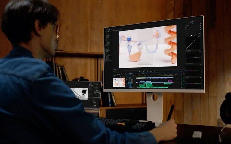 An LG Smart Monitor being used for video editing in a compact, space-efficient setup. The desk is neatly organised, and the monitor displays editing software with a clean interface. The setting emphasises efficient use of space in a cozy, wood-panelled workspace.