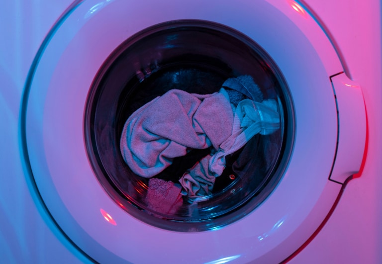 Clothes inside a dryer illuminated with pink and blue lighting