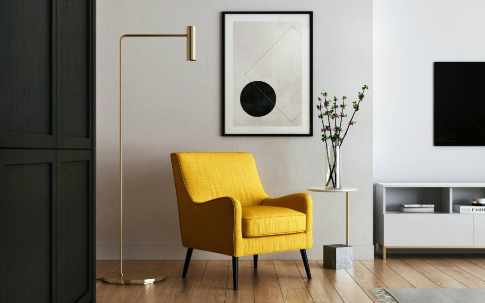 Modern living room in a smart home with a yellow armchair, geometric artwork, floor lamp, and TV