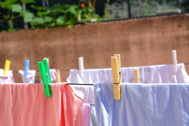 Clothes in various colours hanging on a clothesline with plastic clothespins