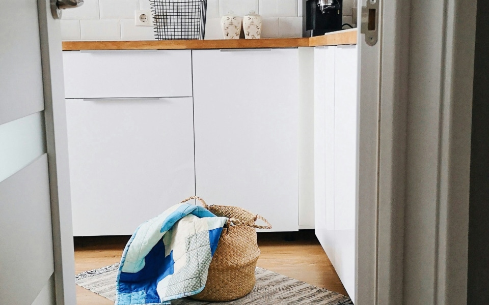 A laundry basket lies on a textured rug in a modern kitchen