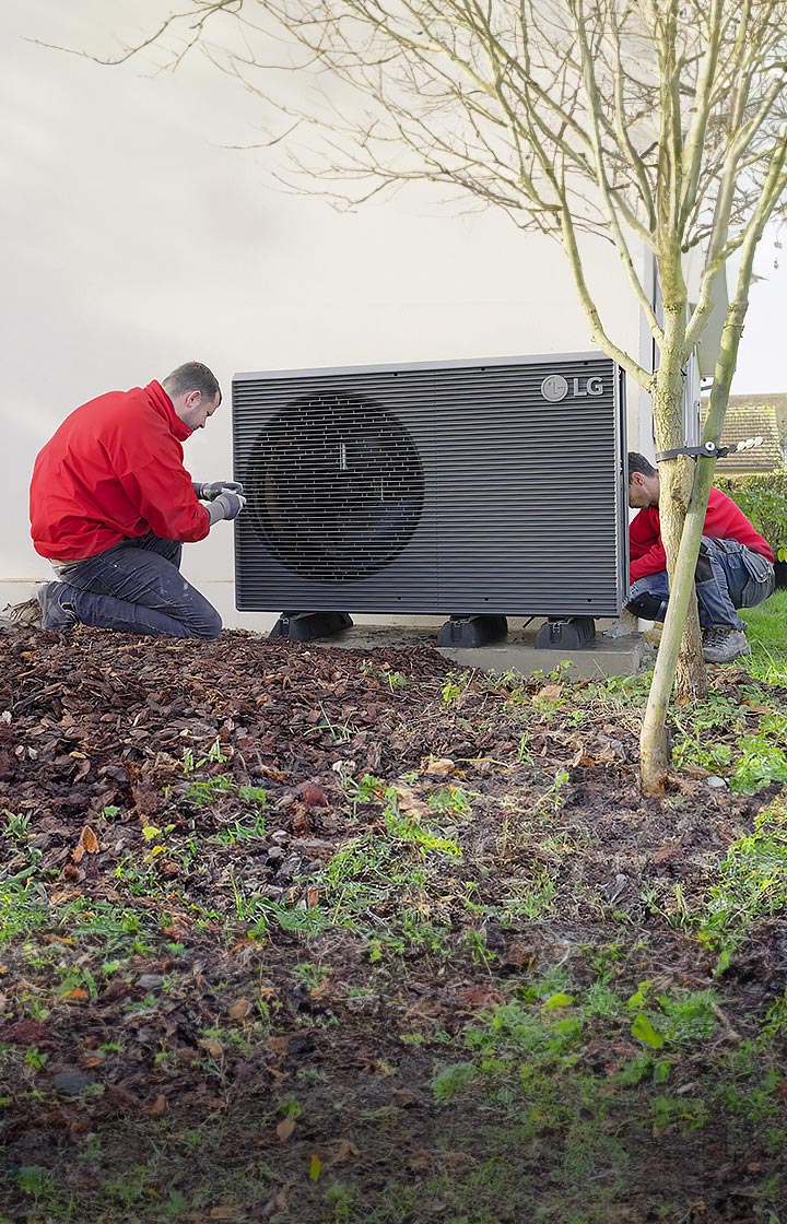 Two installers with red jumpers uniform install LG Air to Water Heat Pump THERMA V R290 Monobloc in the backyard of house.