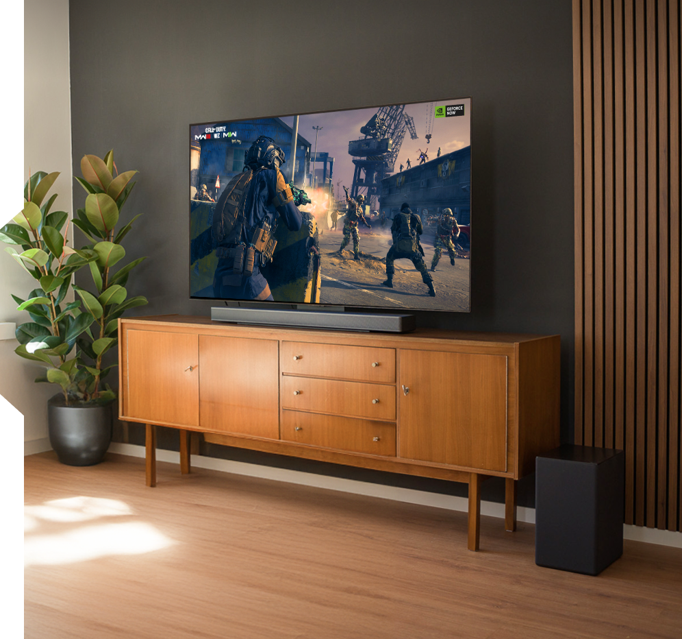 A TV displaying a game with a subwoofer on the floor.