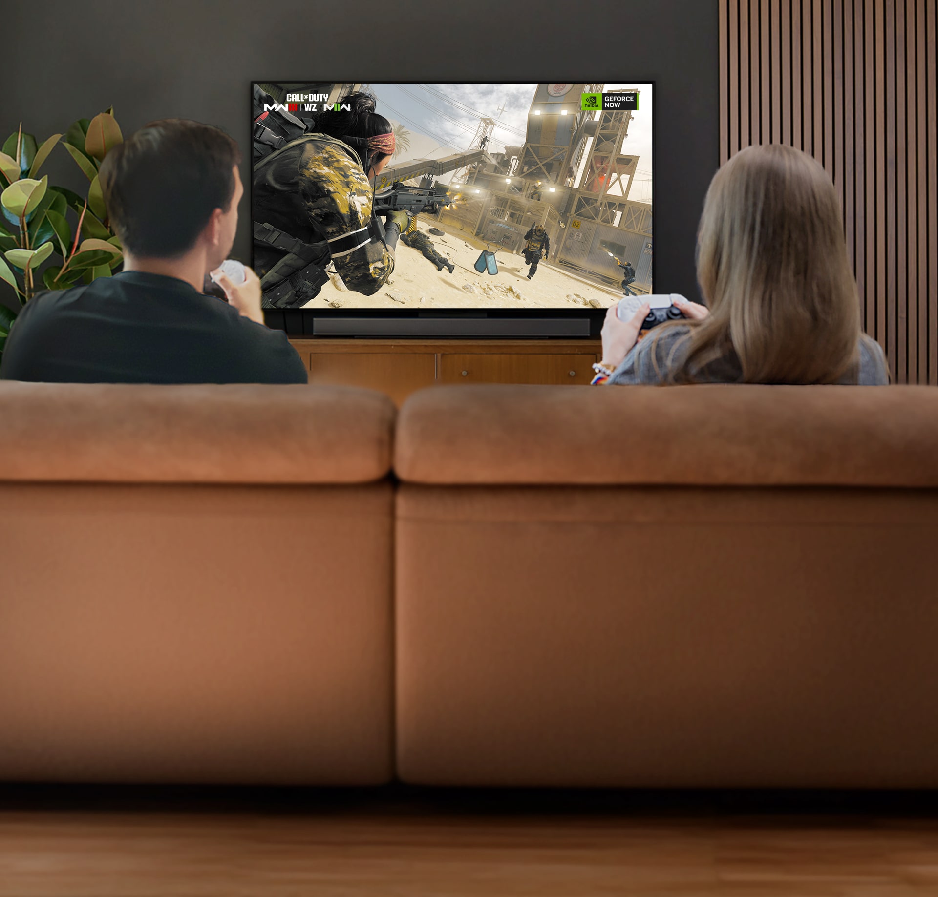 Two people playing Call of Duty on a large screen TV.