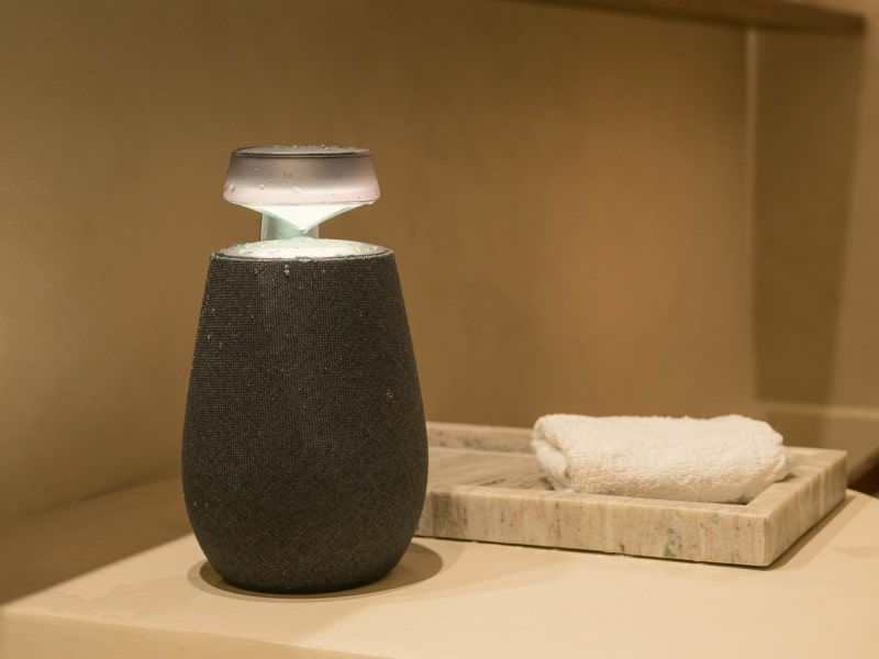 In the bathroom, an LG Xboom XO2T wireless speaker with the Mood Lighting feature turned on is placed next to a hand towel.