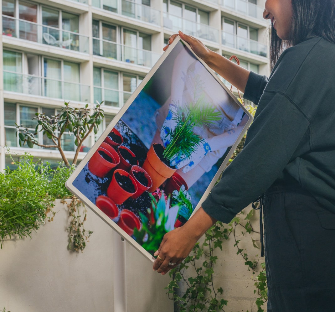 Lisa Mistry is adjusting the angle of the LG StandbyME, which is playing a video about repotting plants, while on her balcony.