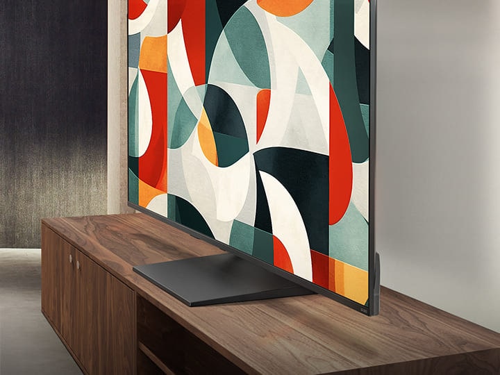 LG QNED TV standing above a TV drawer in a modern living space. LG QNED TV depicts an abstract background in green, red and orange.