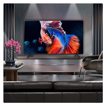 A family sits on a couch facing a LG QNED TV sitting above a TV stand with a little girl pointing to a screen depicting two dolphins. The title talks about how you can enjoy high resolution on a massive screen.