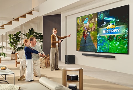 Family of 3 playing a game in a living room with a LG TV mounted on a wall above a LG Soundbar. Zero Connect Box sits inside a coffee table.