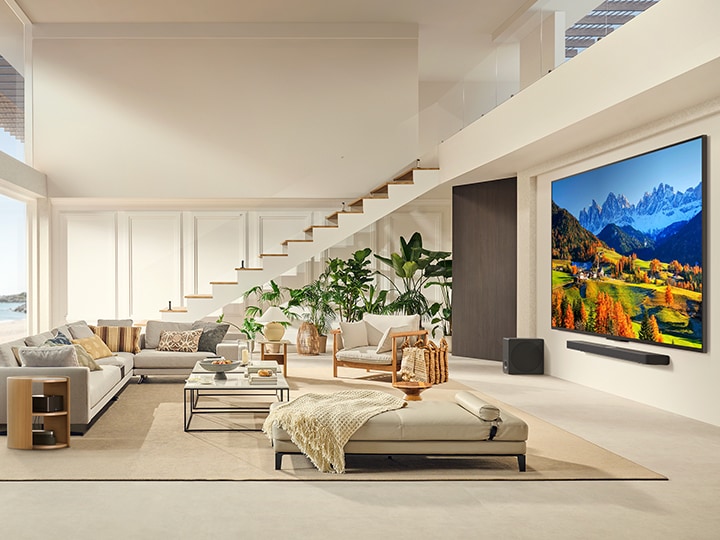 LG QNED TV mounted on a wall above a LG Soundbar in a modern living room space.  Zero Connect Box sits inside a coffee table.