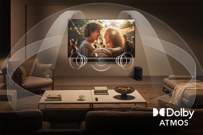 Dimly lit, cozy living room with a couple watching a movie on their LG QNED TV with LG Soundbar. Graphics show how Dolby Atmos fills the whole space with surround sound from all directions. Dolby Atmos logo is at the bottom corner.