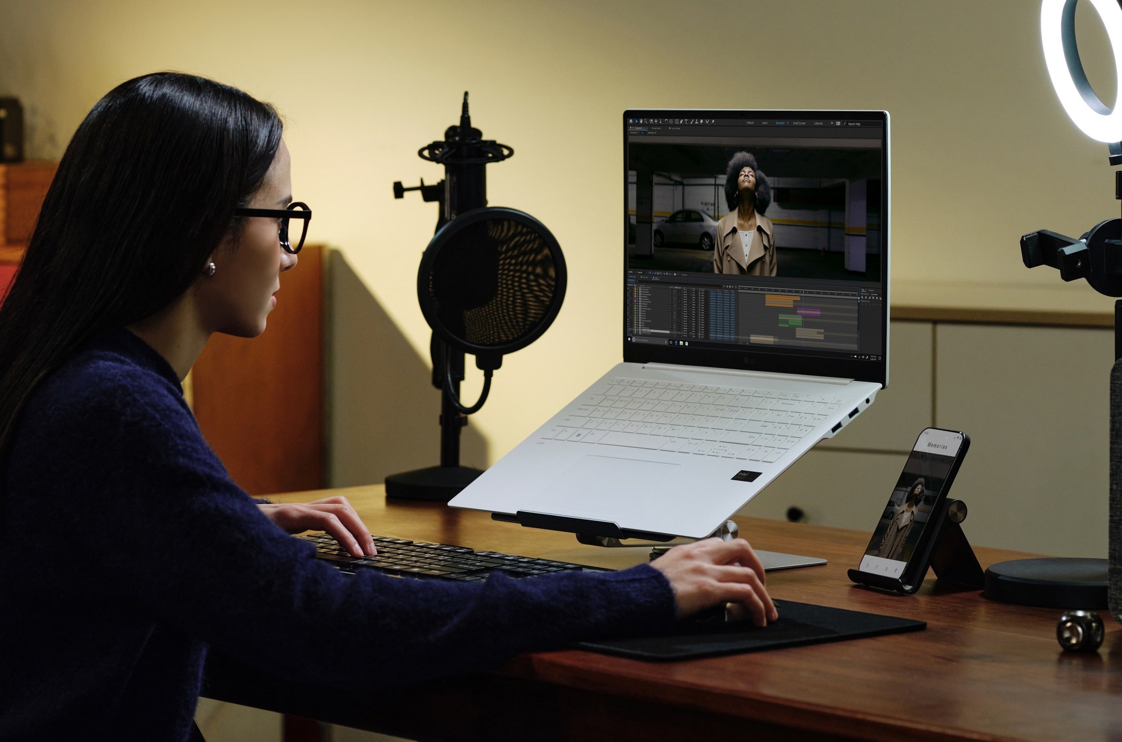 A woman is sat a wooden desk editing an image on her LG laptop