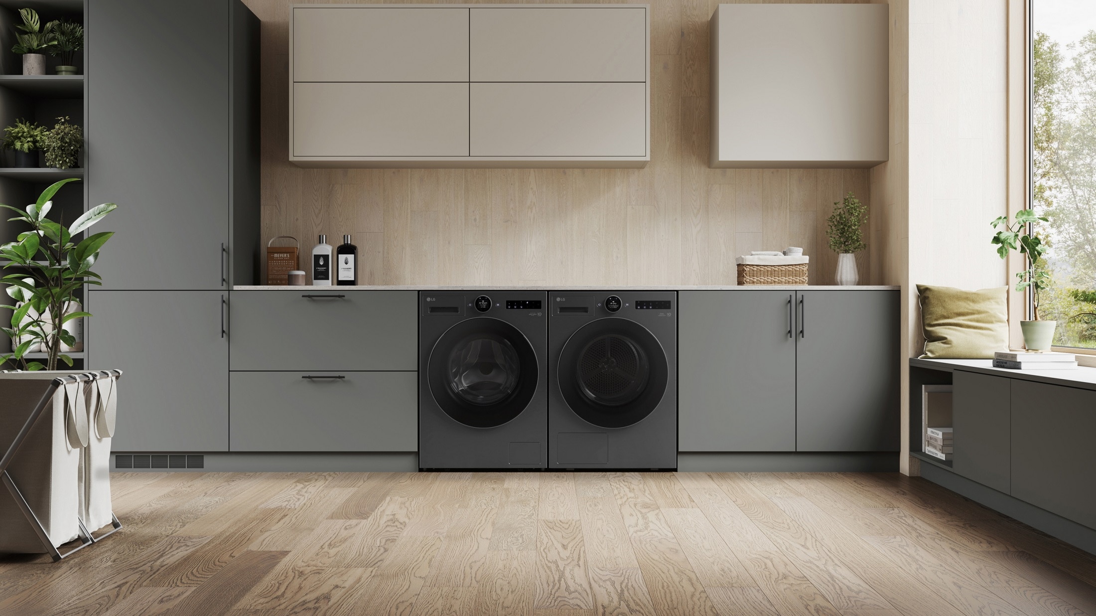 LG washing machine and tumble dryer in the centre of a modern, dark grey kitchen unit, with wooden floors and walls