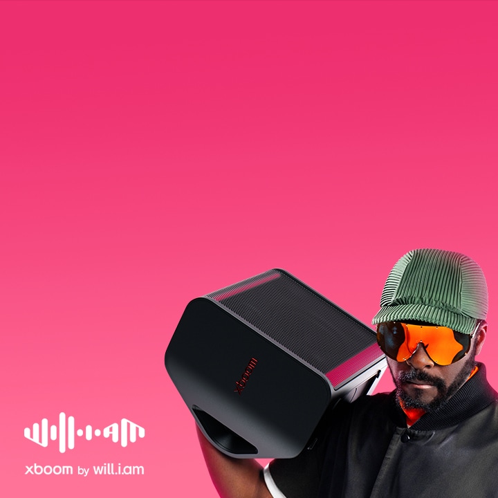 will.i.am in black outfit and sunglasses is holding xboom Stage 301 on his shoulder.