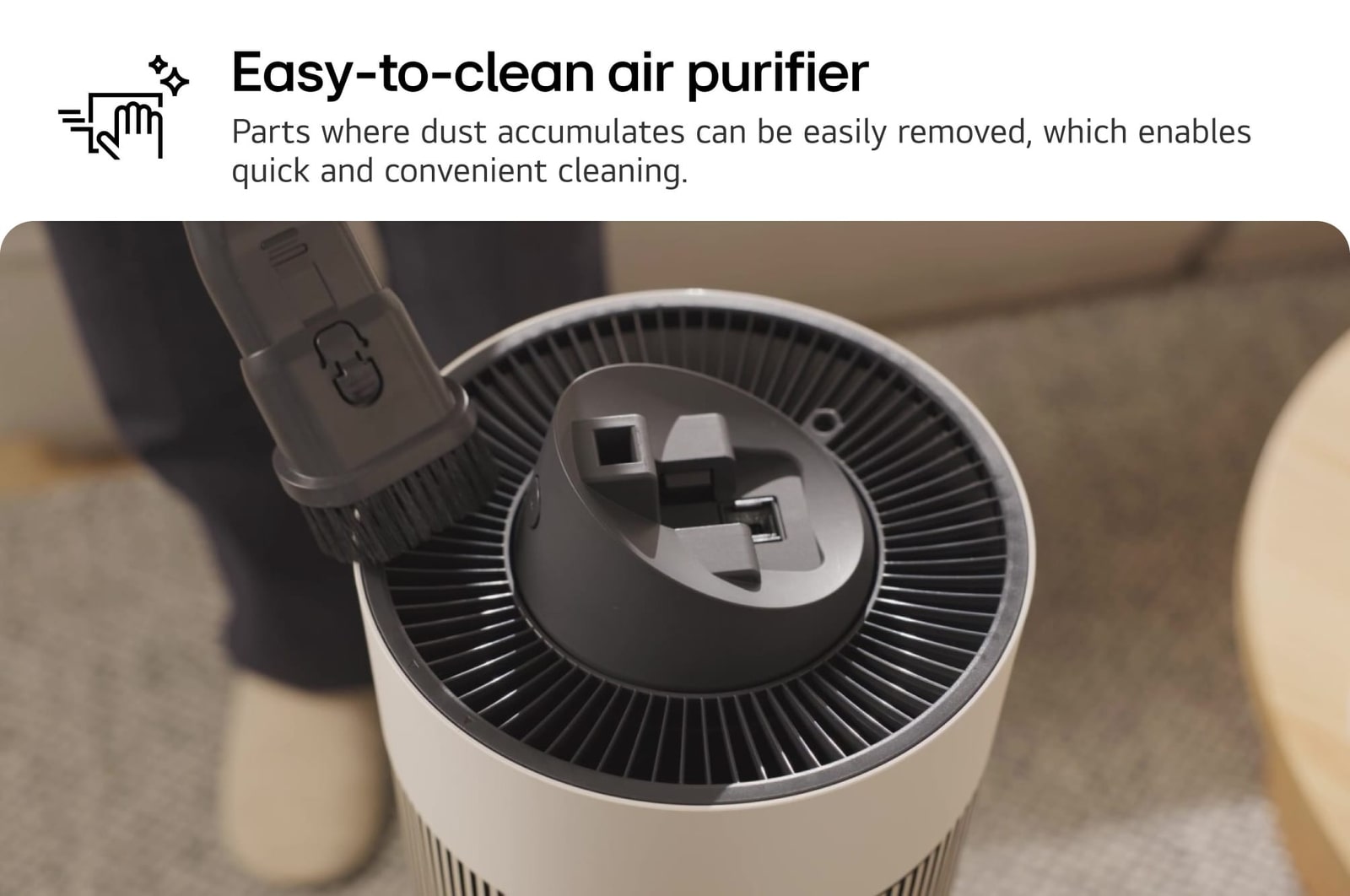 Top view of an LG air purifier being cleaned with a brush attachment. Text reads: 'Easy-to-clean air purifier: Parts where dust accumulates can be easily removed, enabling quick and convenient cleaning.'