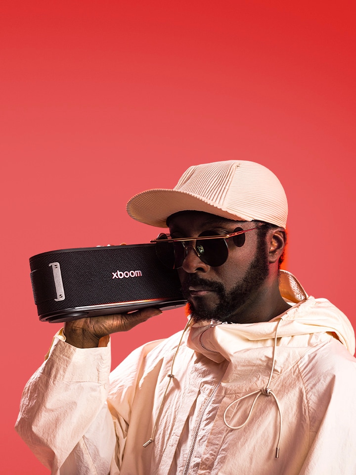 will.i.am trong trang phục trắng và đeo kính râm, đang cầm chiếc xboom Bounce sát bên mặt.