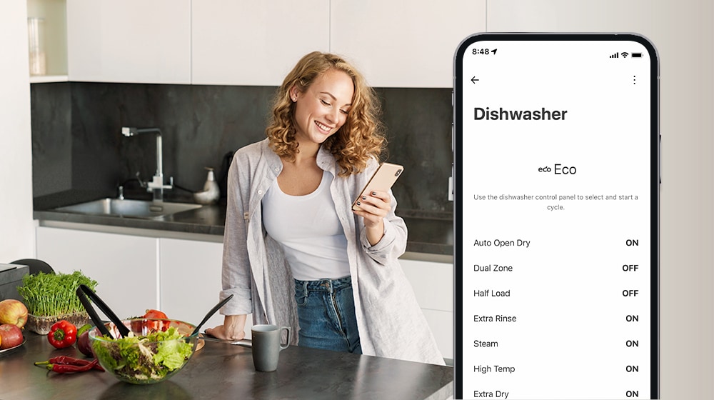 Một người phụ nữ đang xem điện thoại di động trong nhà bếp và điện thoại thông minh hiển thị cài đặt cá nhân hóa trong ứng dụng ThinQ™.