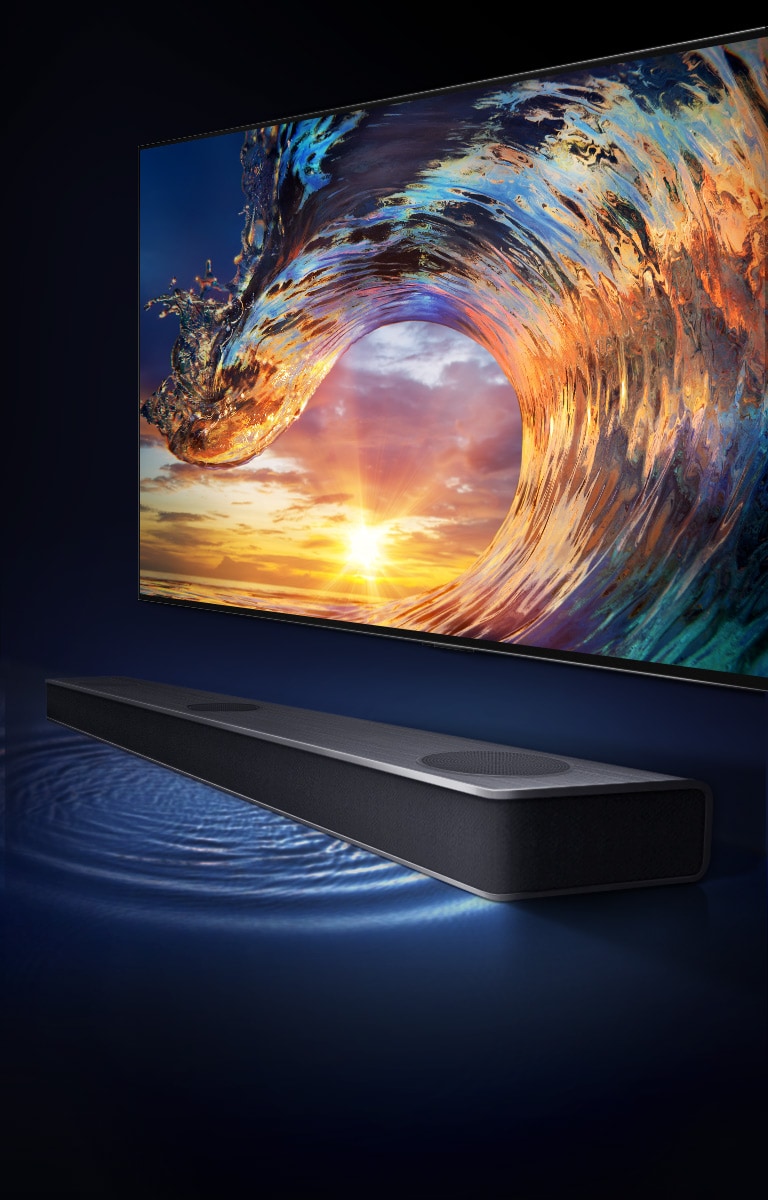 TV cho thấy cảnh bầu trời hoàng hôn và những con sóng màu cầu vồng. Có loa sound bar bên dưới TV và bước sóng âm thanh trên sàn nhà.